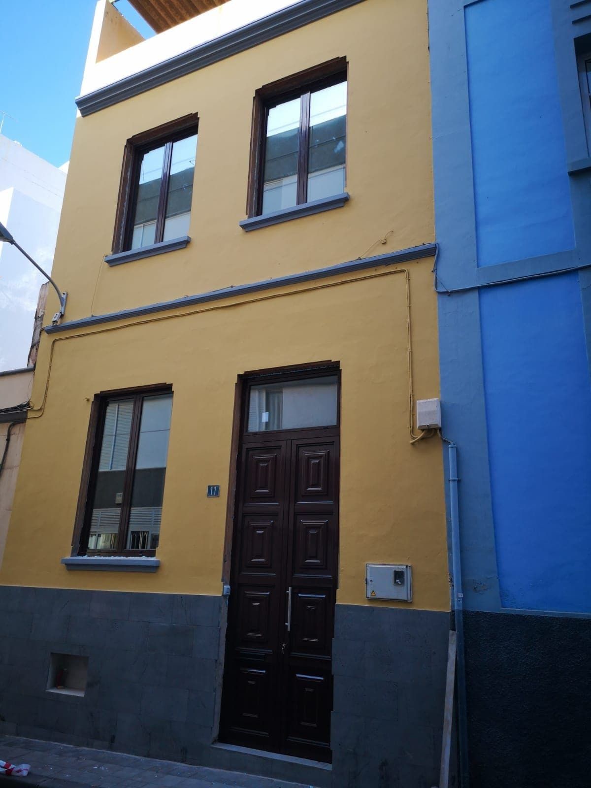 Un edificio amarillo con un edificio azul al fondo.