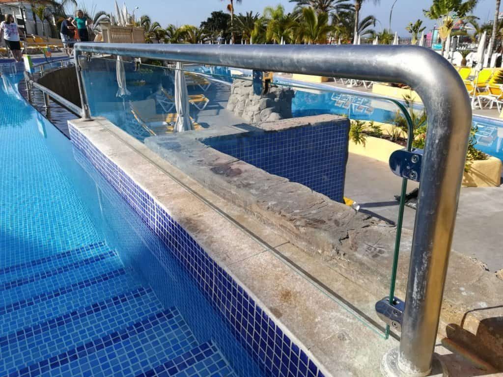 Una piscina con barandilla de acero inoxidable y azulejos azules
