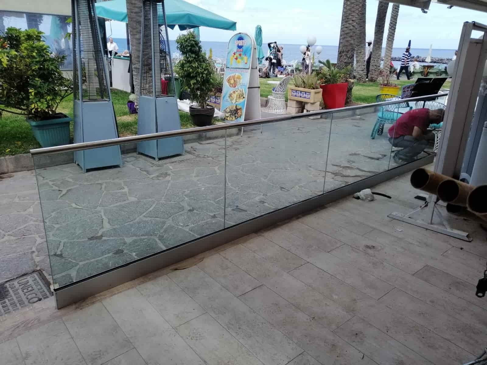 Se está instalando una barandilla de vidrio en un balcón con vista al océano.