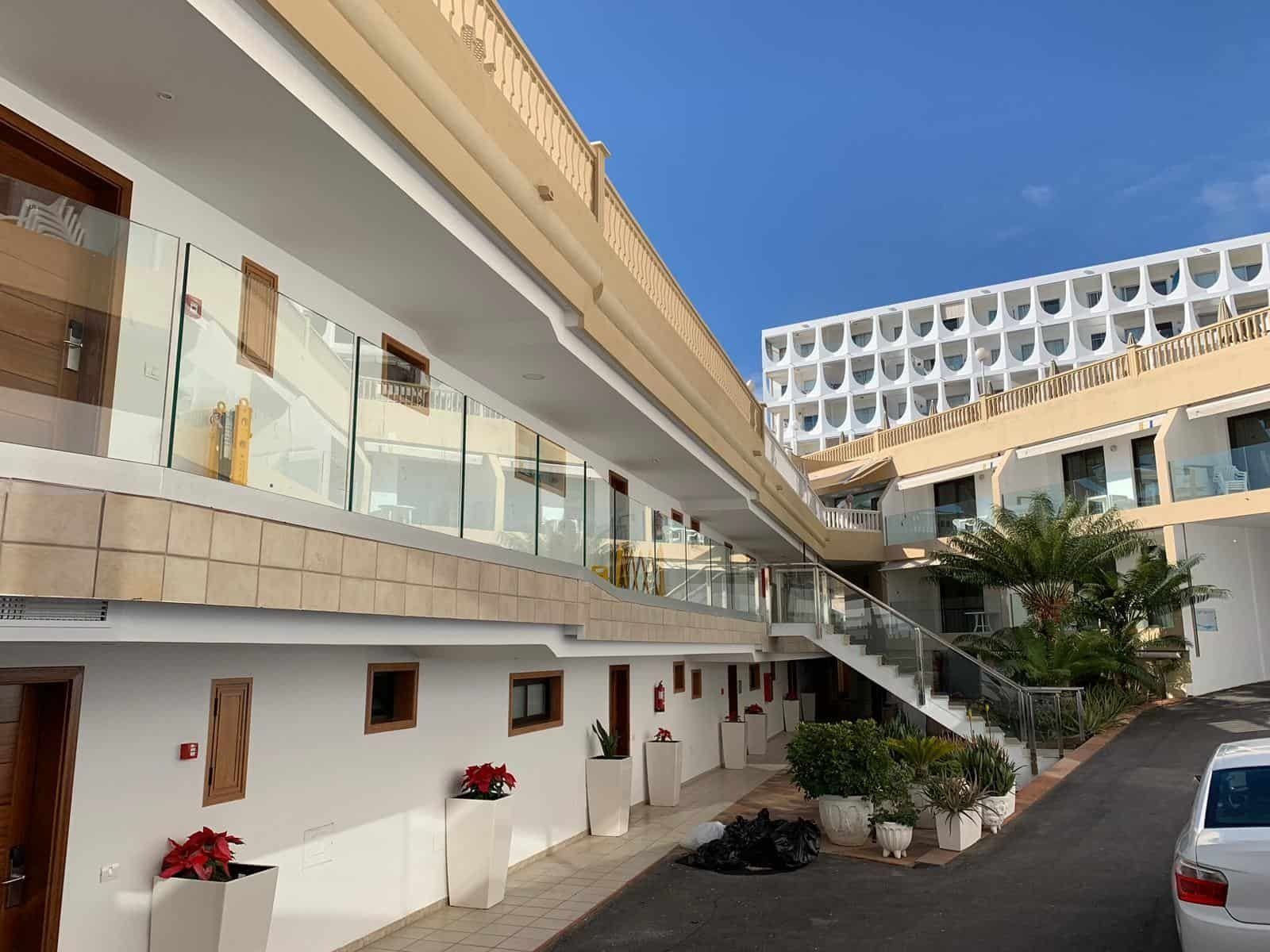 Un coche blanco está aparcado delante de un hotel.