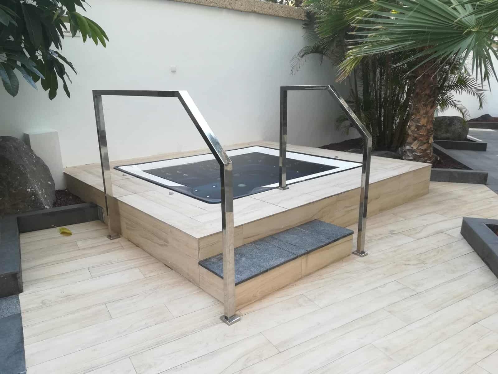 Un jacuzzi con escaleras y barandilla de acero inoxidable.