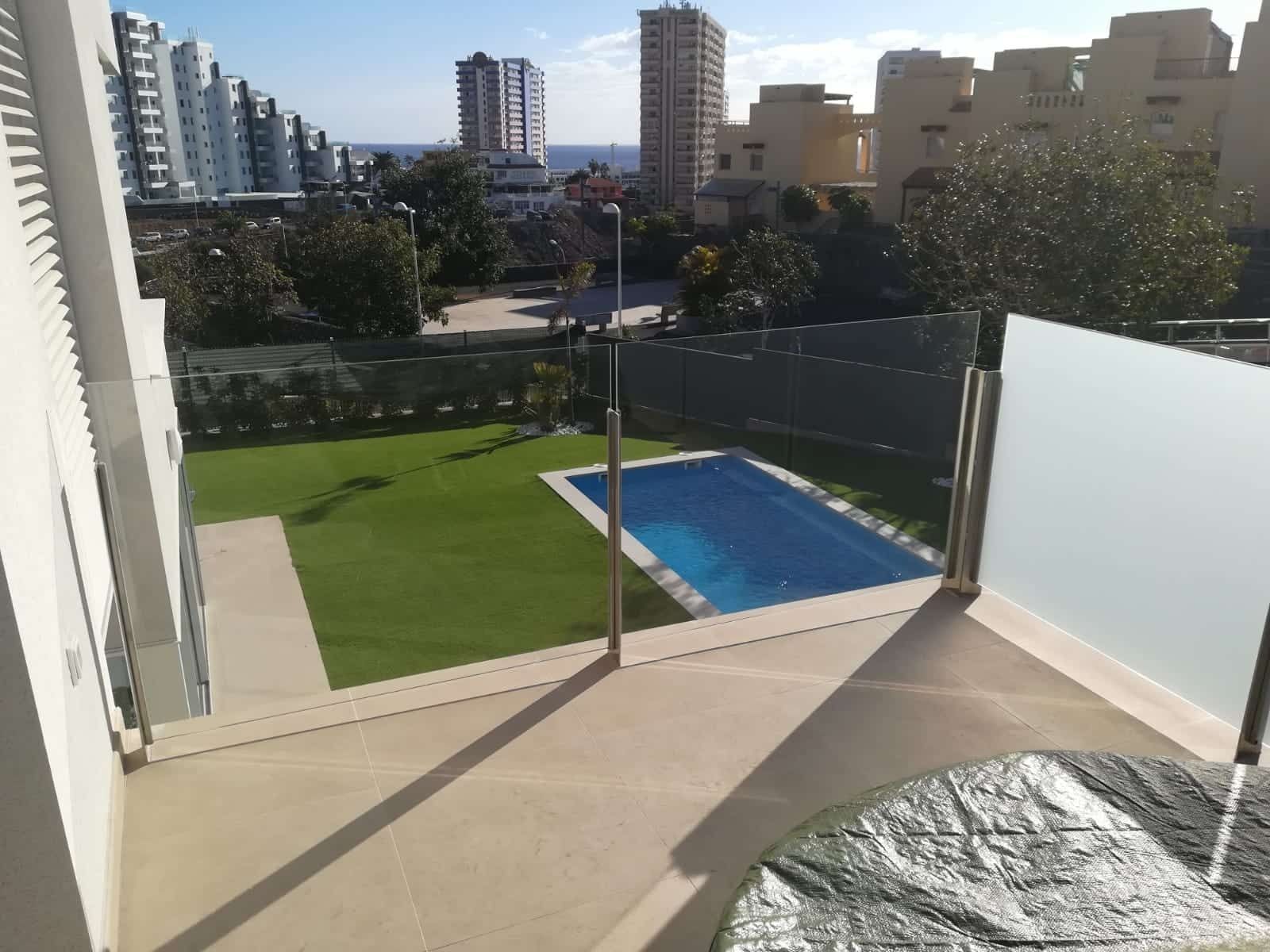Un balcón con vistas a una piscina con una ciudad al fondo.