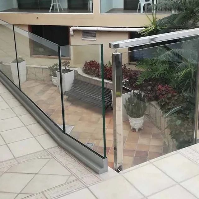 Un balcón con barandilla de cristal y un banco.