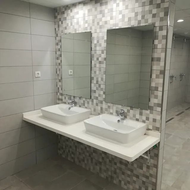 Un baño con dos lavabos y dos espejos.