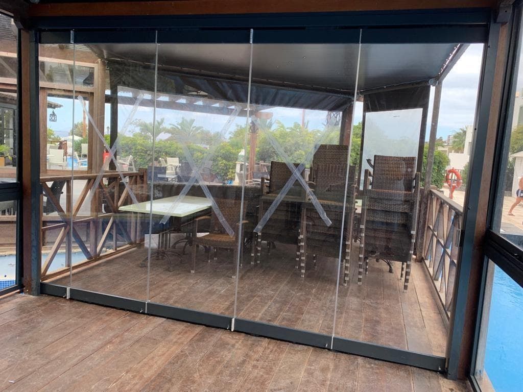 Una habitación con una mesa y sillas detrás de una pared de cristal.