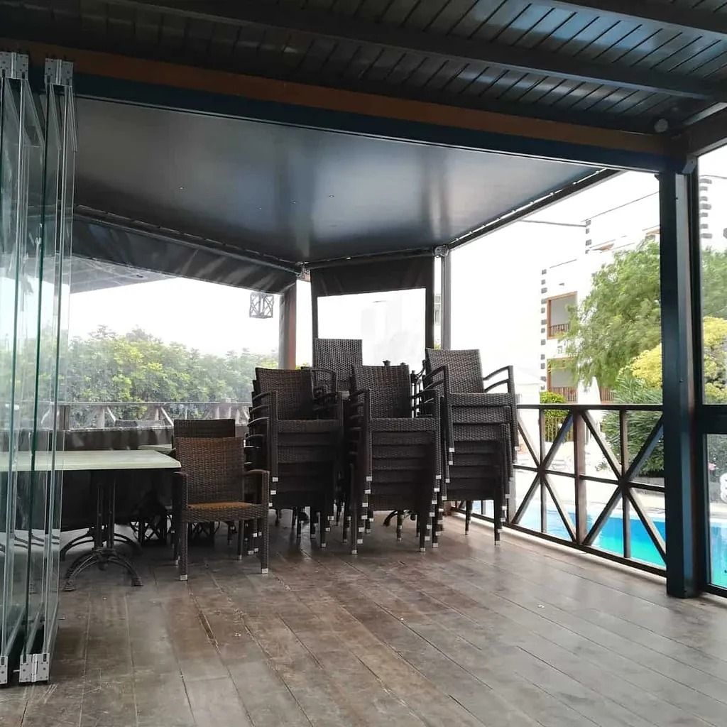 Un patio con una mesa y sillas bajo un dosel.