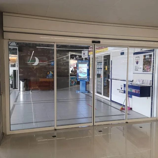 Una gran puerta corrediza de vidrio se abre a una tienda.