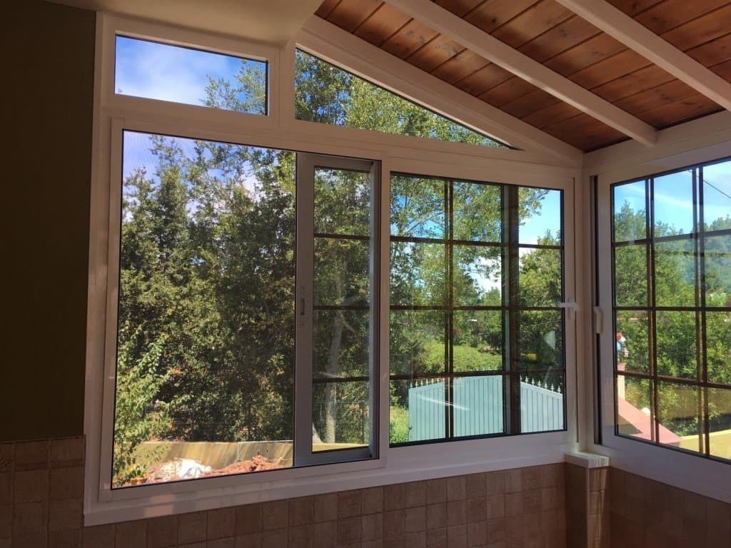 Una habitación con muchas ventanas y árboles al fondo.