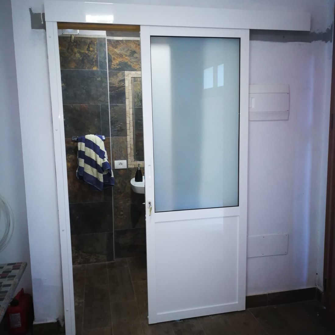 Un baño con puerta corrediza de cristal y lavabo.