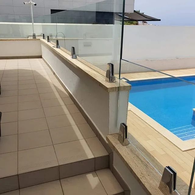 Una piscina con una barandilla de cristal que la rodea.