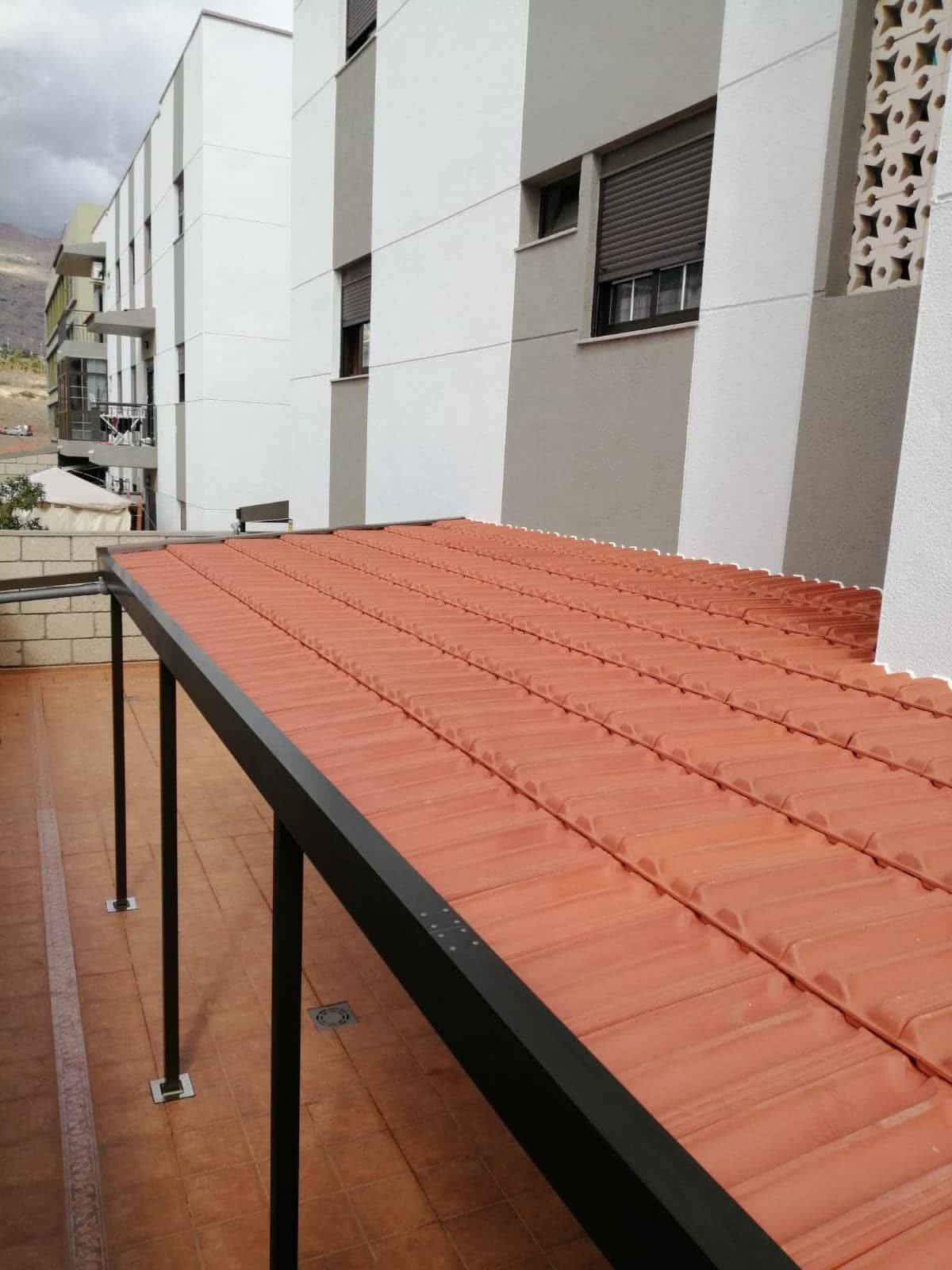 Un techo de tejas rojas con un marco negro delante de un edificio