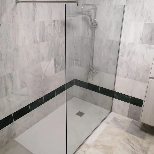 Un baño con ducha a ras de suelo y puerta de cristal.