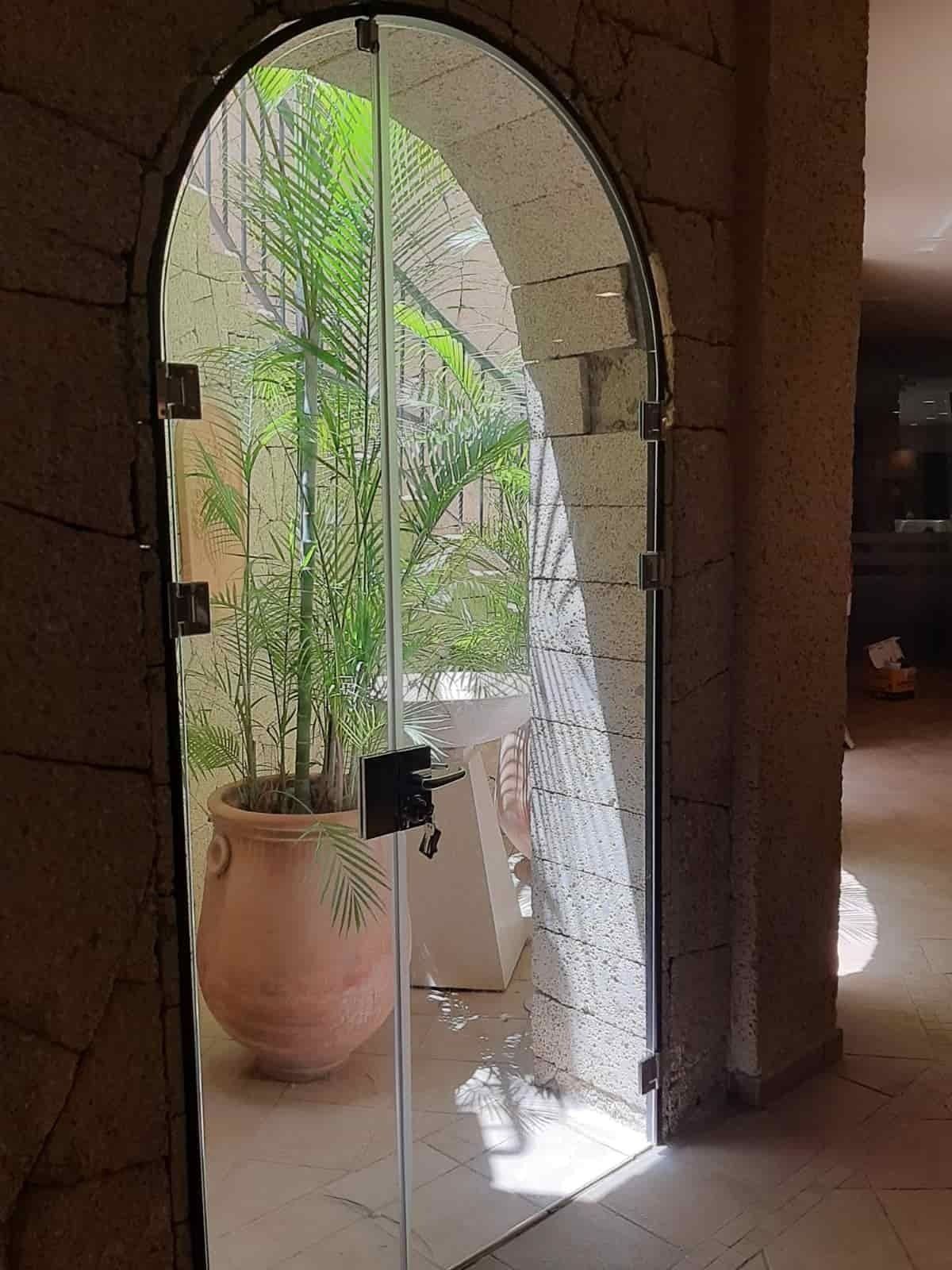 Una puerta de vidrio que conduce a un jardín con plantas en macetas.