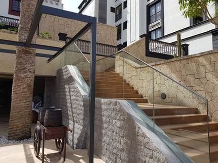 Escaleras que conducen a un edificio con barandilla de cristal.