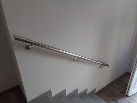 Una escalera con pasamanos de acero inoxidable en la pared.