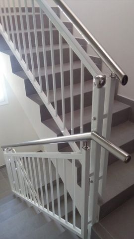 Una escalera con barandilla blanca y pasamanos de acero inoxidable.