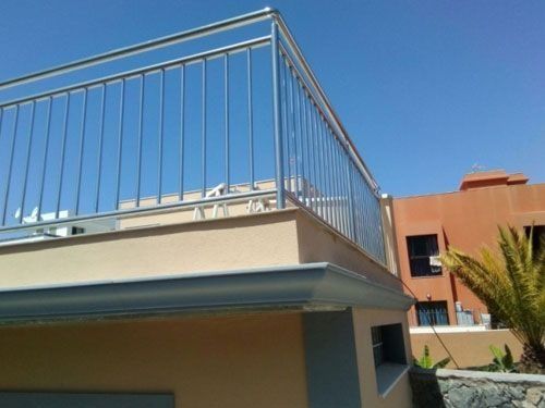 Un balcón con barandilla de acero inoxidable en la parte superior de un edificio.