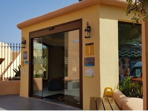 Un edificio amarillo con una puerta corrediza de vidrio que dice 