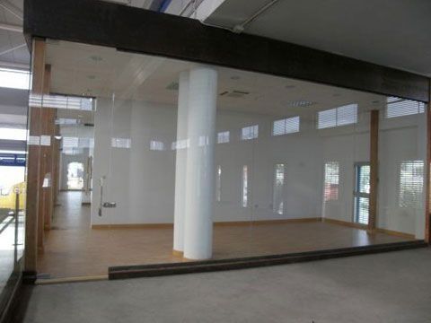 Una gran habitación vacía con una puerta de cristal y columnas.