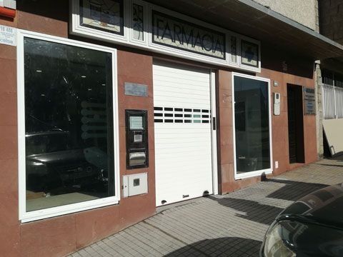 Una farmacia con un coche aparcado delante.