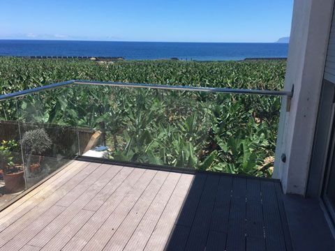 Un balcón con vista a una plantación de plátanos y al océano.