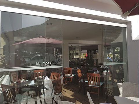 Un restaurante con mesas y sillas frente a una puerta de cristal.
