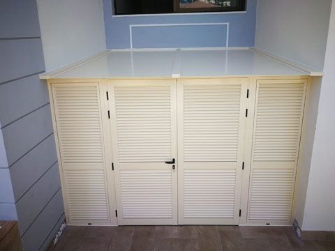 En una habitación hay un armario blanco con persianas en las puertas.