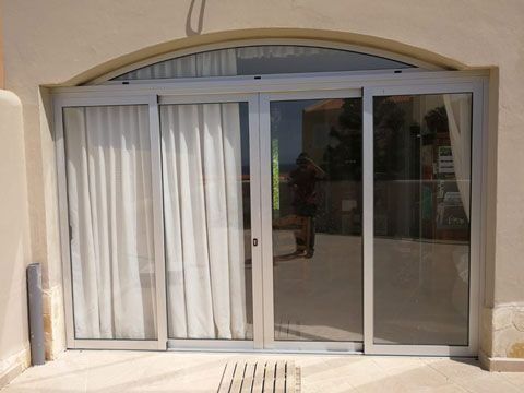 Una gran puerta corrediza de vidrio con cortinas blancas.