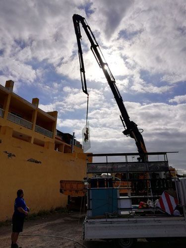 Un hombre está de pie junto a un camión con una grúa acoplada a él.