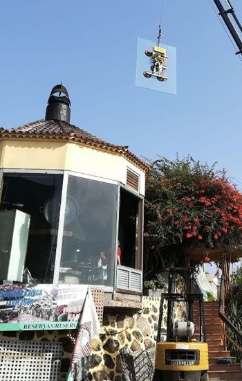 Una grúa está levantando un trozo de vidrio sobre un edificio.