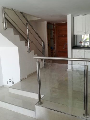 Una escalera con barandilla de acero inoxidable y barandilla de vidrio.