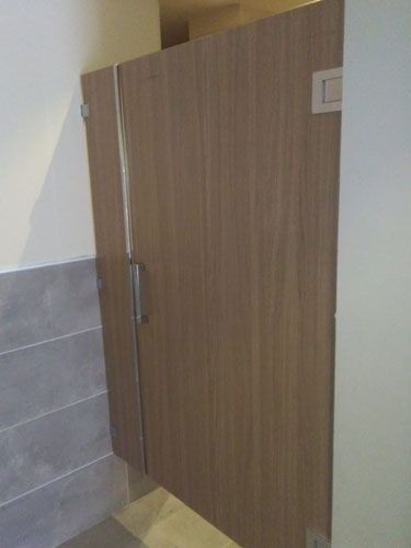 Un cubículo de baño con una puerta de madera y una puerta de cristal.