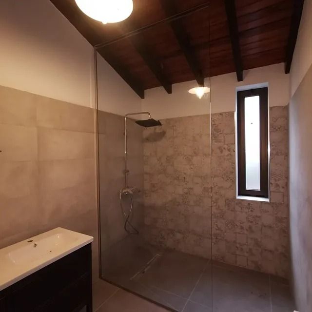 Un baño con ducha a ras de suelo y ventana.