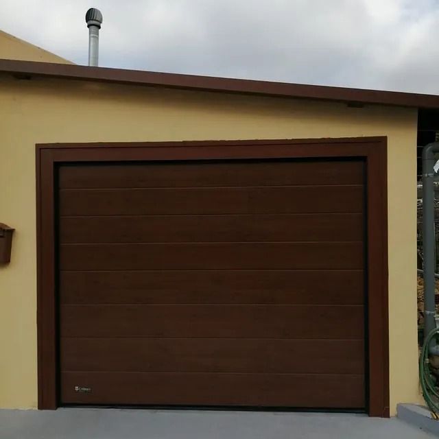 Una puerta de garaje marrón en un edificio amarillo