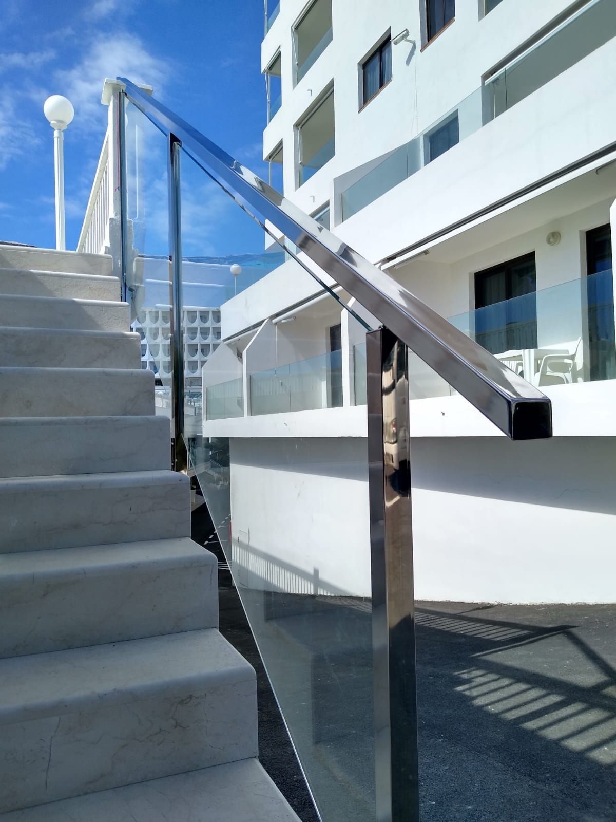 Escaleras que conducen a un edificio con barandilla de cristal.