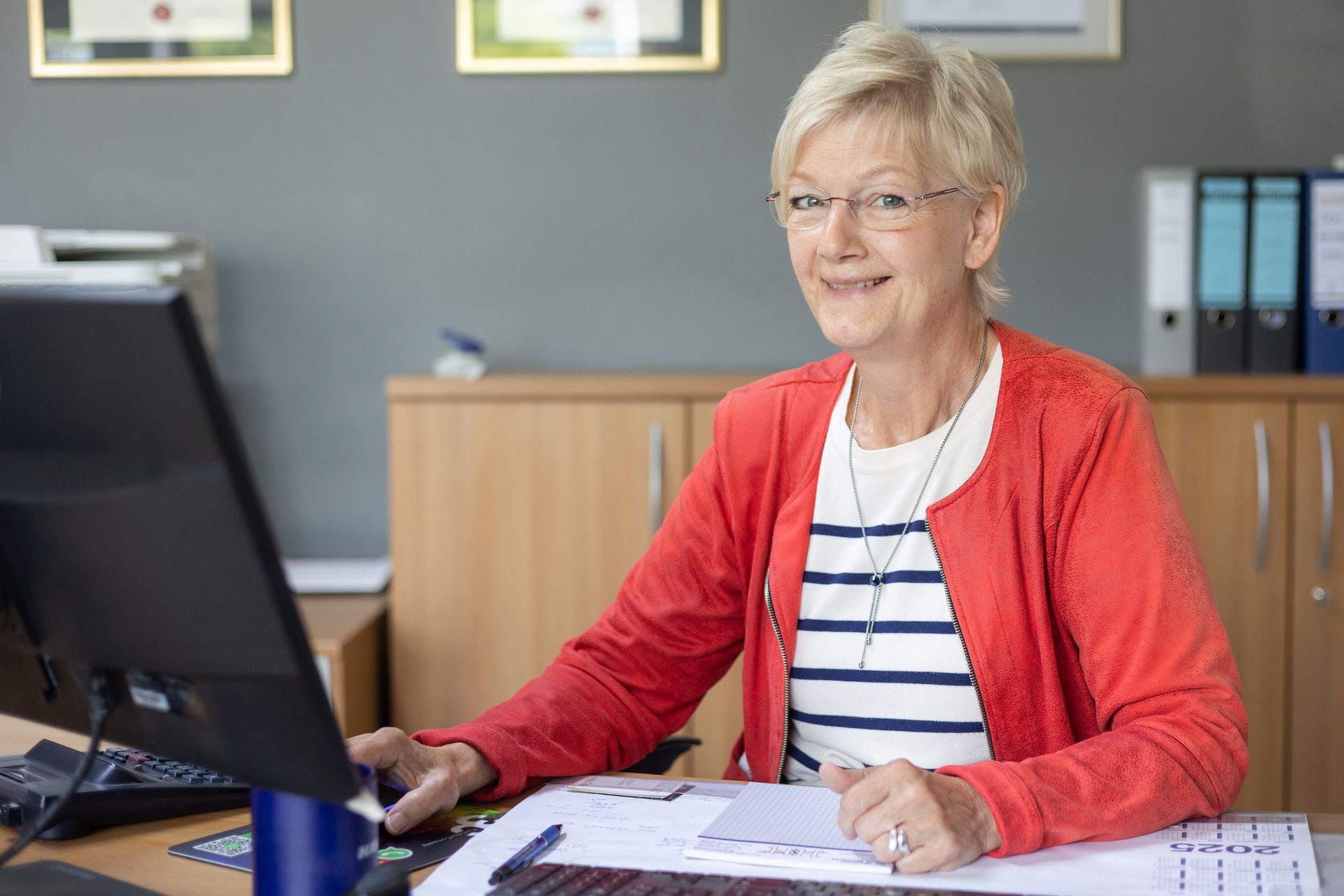 Eine Frau sitzt an einem Schreibtisch vor einem Computer.