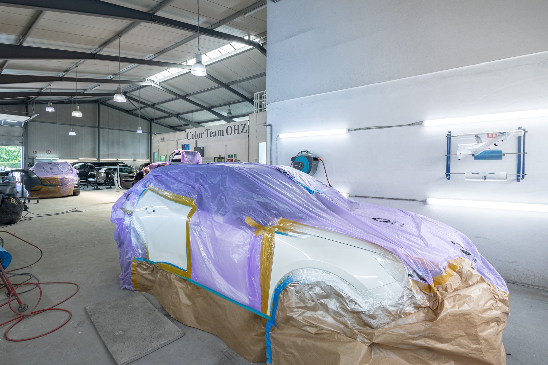 Ein Auto wird beim Lackieren in einer Garage mit Plastik abgedeckt.