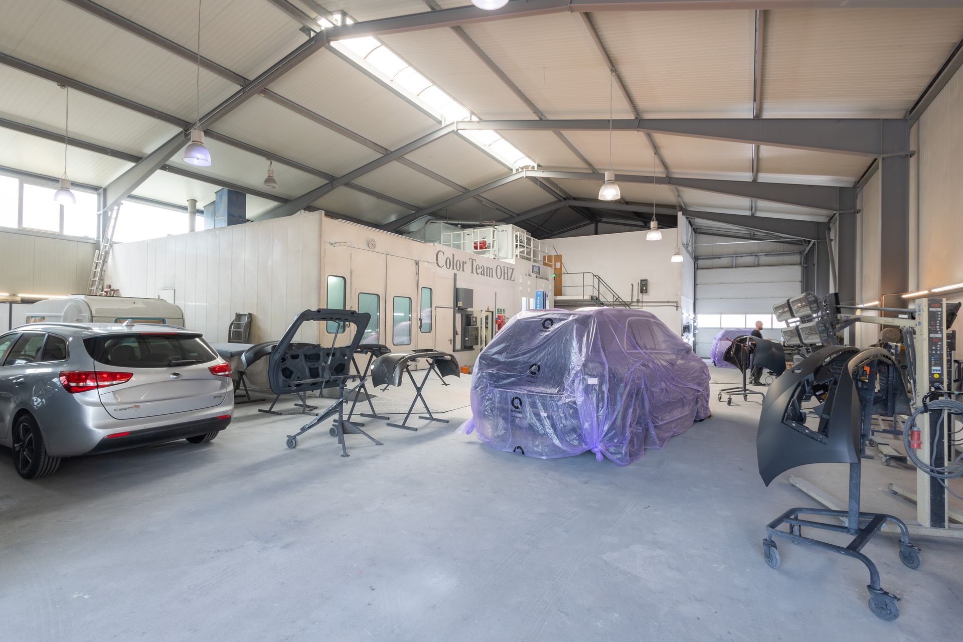 Ein Auto steht in einer Garage mit Plastikfolie abgedeckt.