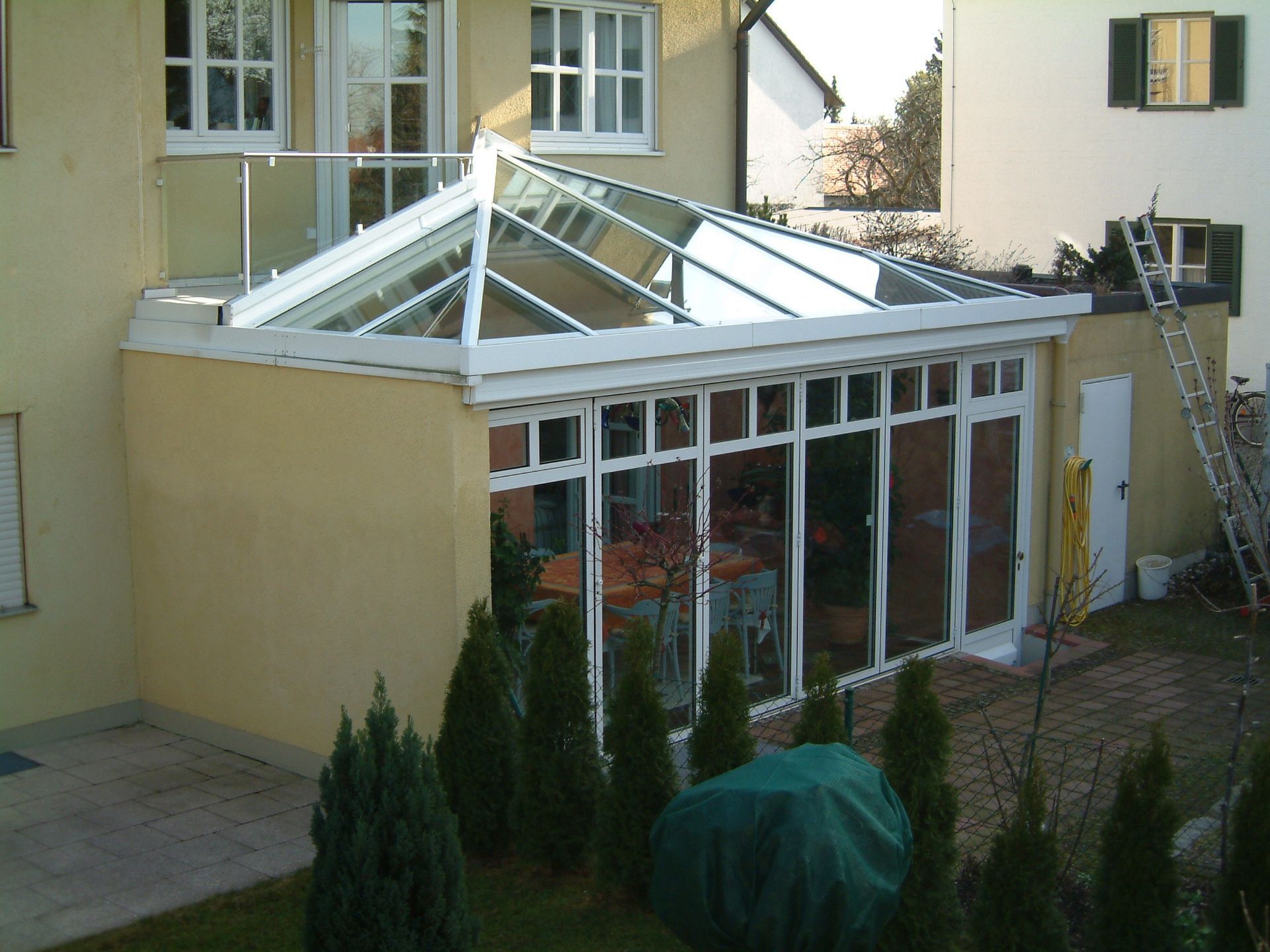 Kleiner verglaster Wintergarten an einer Hausfassade.