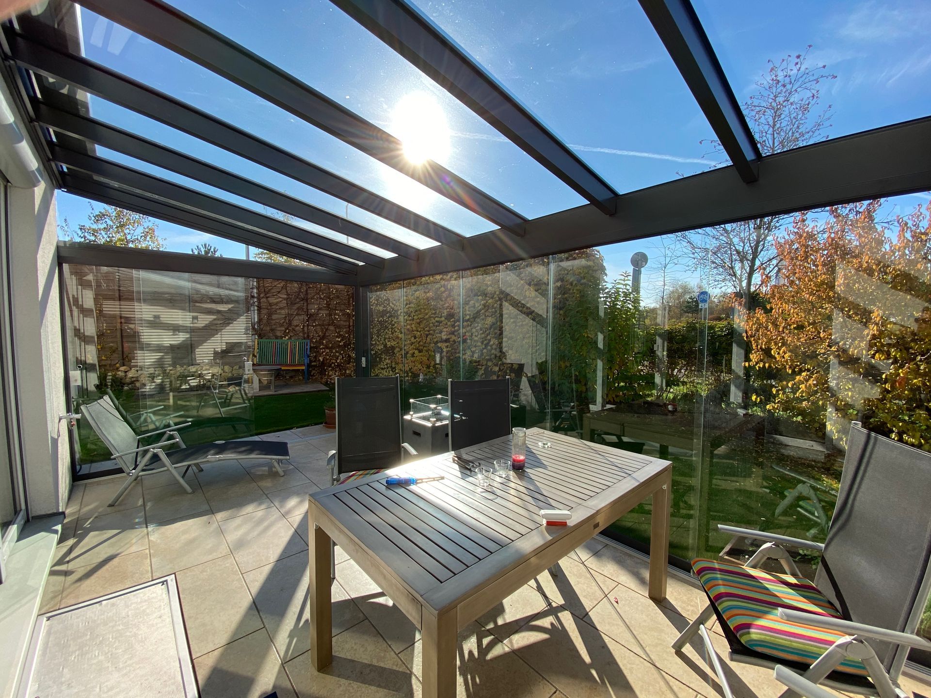 Offener Wintergarten mit Glasdach und Terrasse.