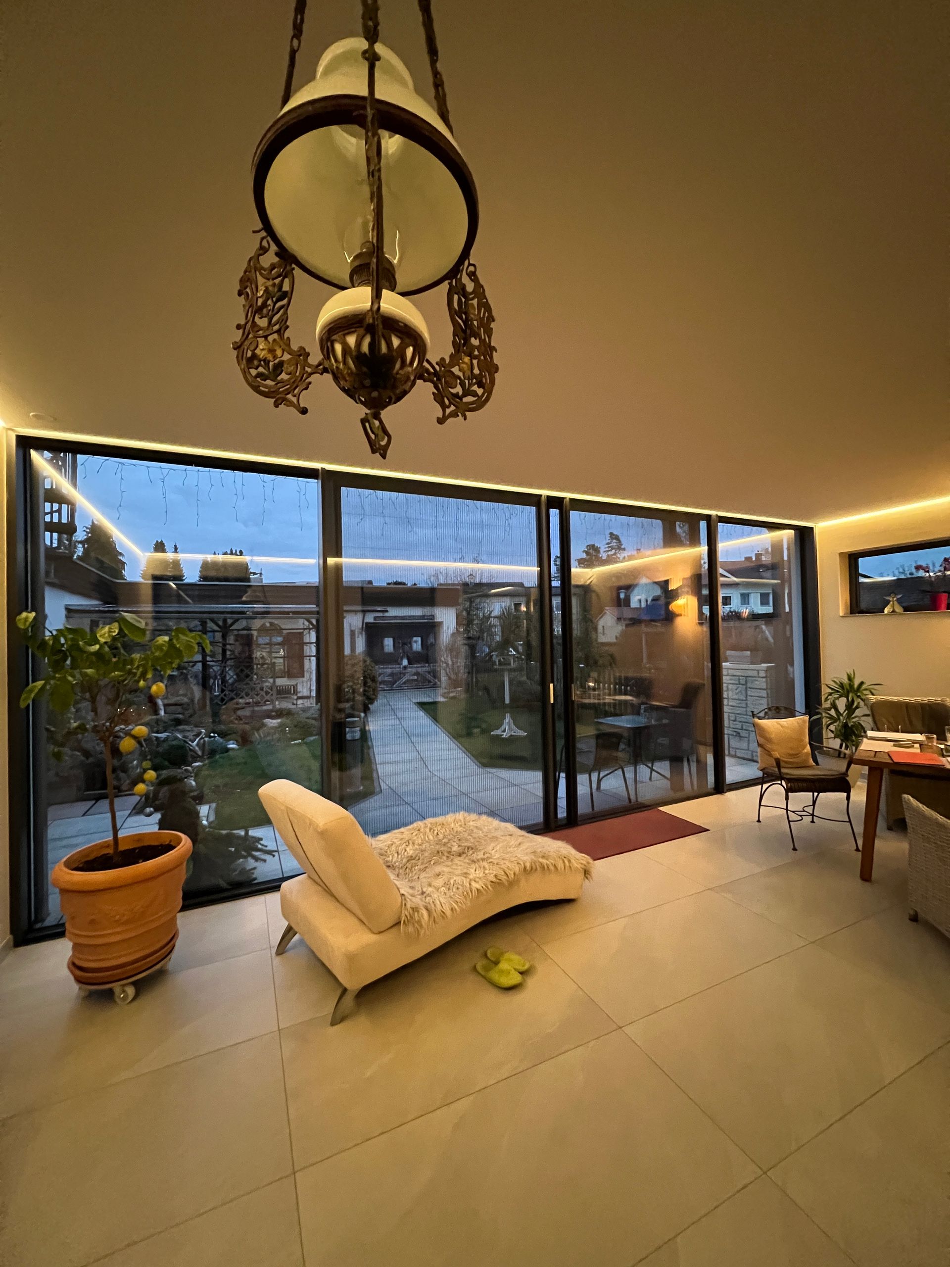 Heller Wintergarten mit Liegestuhl und großem Glasfrontblick.