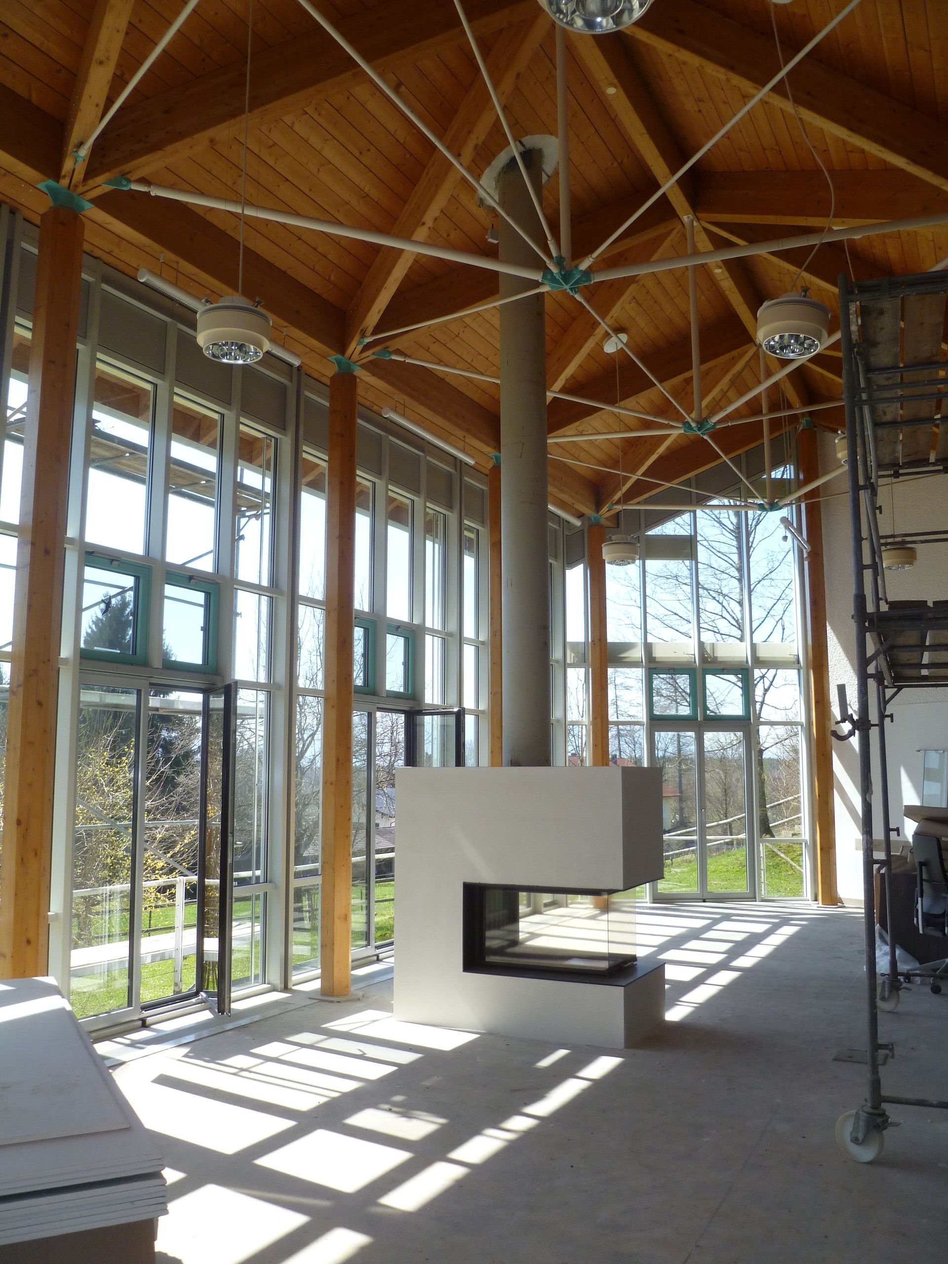 Hoher Wintergarten mit Holzdecken und großen Glasflächen.