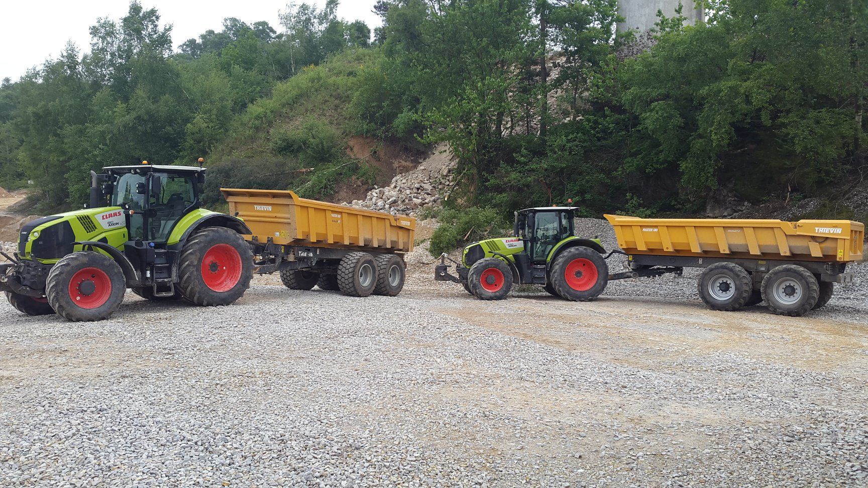 Des pièces métalliques peintes en blanc sont suspendues à des crochets à l'intérieur d'une cabine de peinture.
