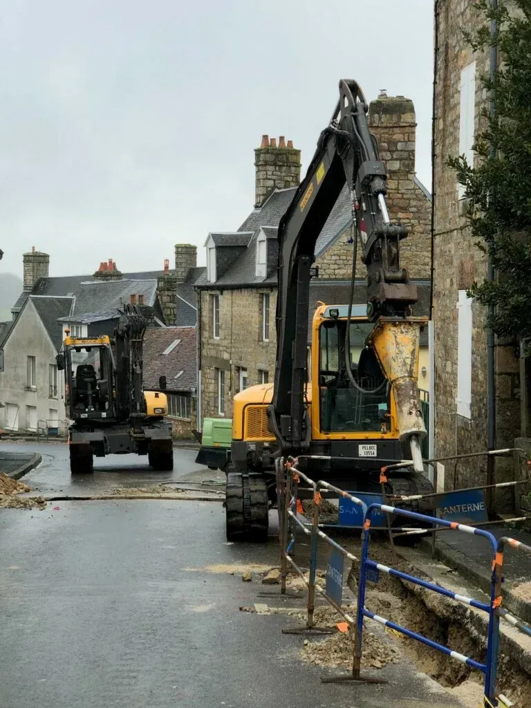 Des pièces métalliques peintes en blanc sont suspendues à des crochets à l'intérieur d'une cabine de peinture.
