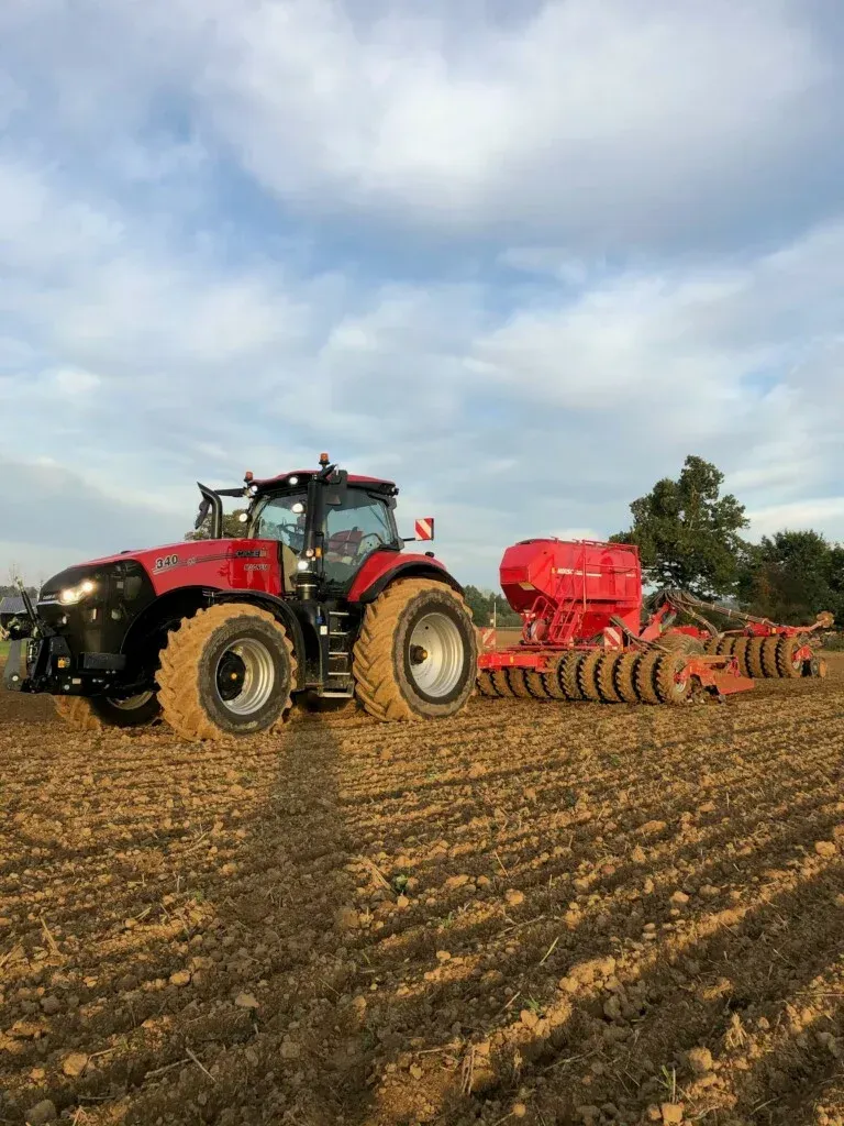Des pièces métalliques peintes en blanc sont suspendues à des crochets à l'intérieur d'une cabine de peinture.