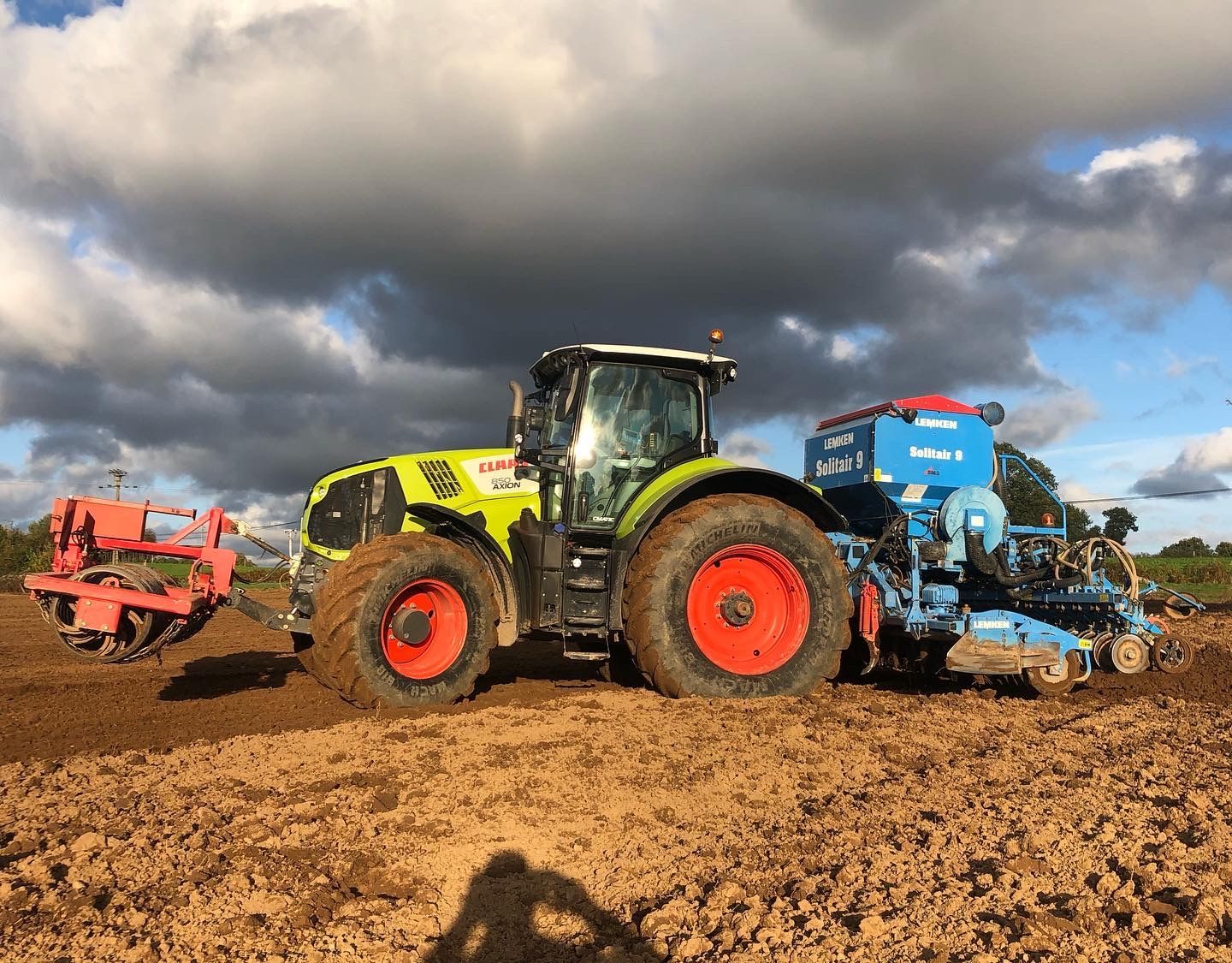Des pièces métalliques peintes en blanc sont suspendues à des crochets à l'intérieur d'une cabine de peinture.