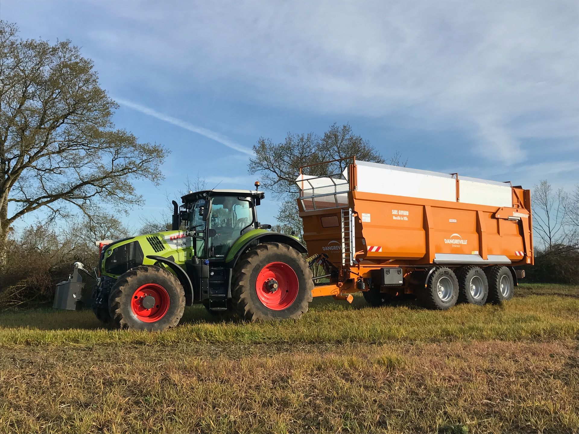 Tracteur vert tirant une remorque orange.