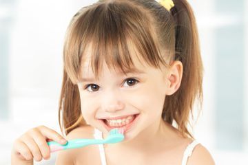 Una niña se cepilla los dientes con un cepillo de dientes.