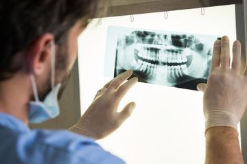 Un dentista está mirando una radiografía de los dientes de una persona.