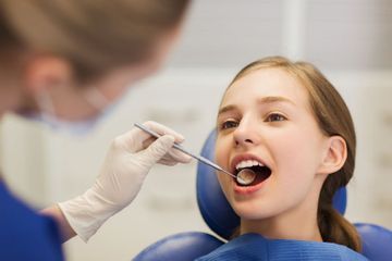 Una mujer está siendo examinada por un dentista.